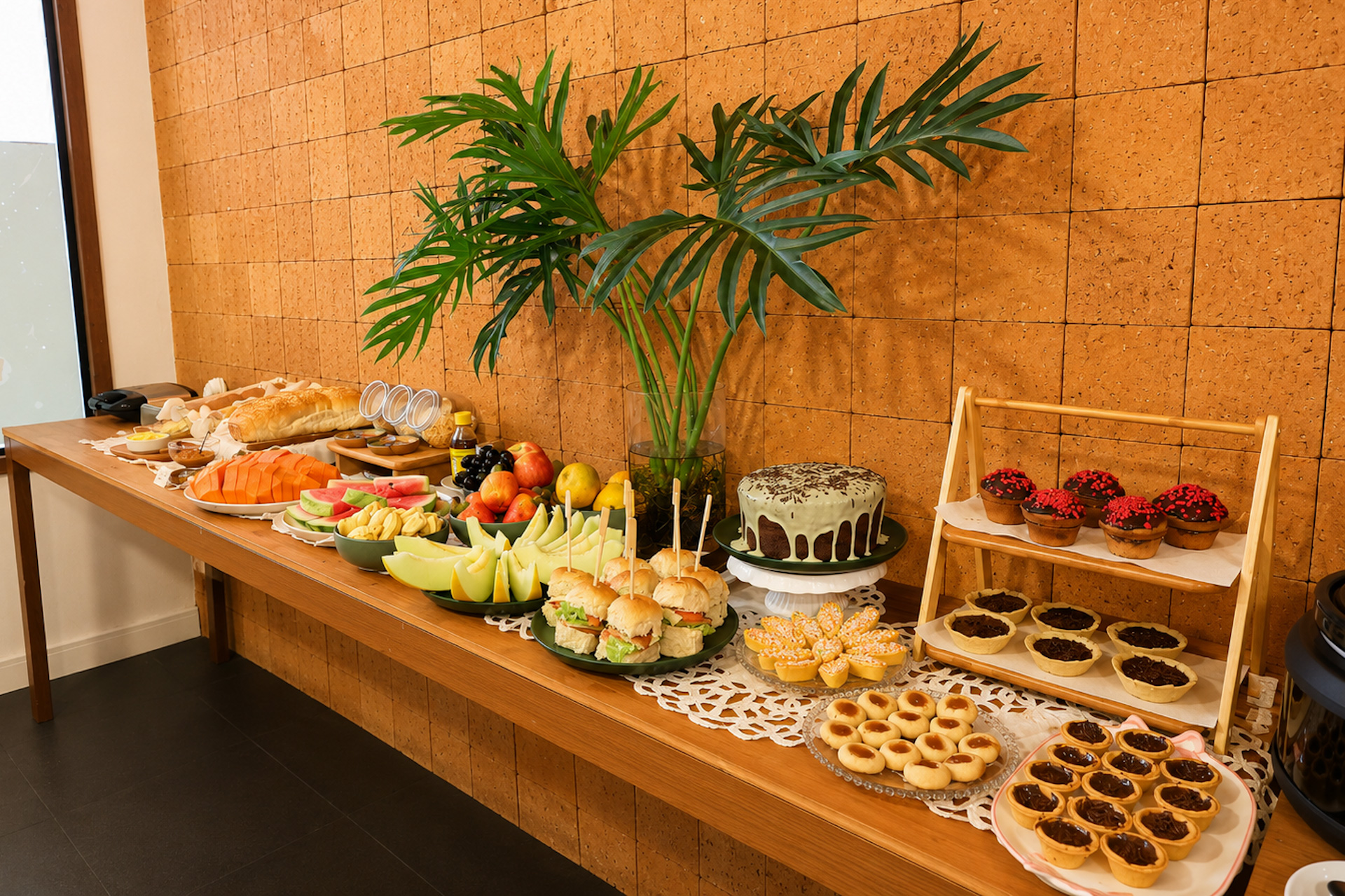Mesa de café da manhã com pães, bolo, tortinhas e frutas