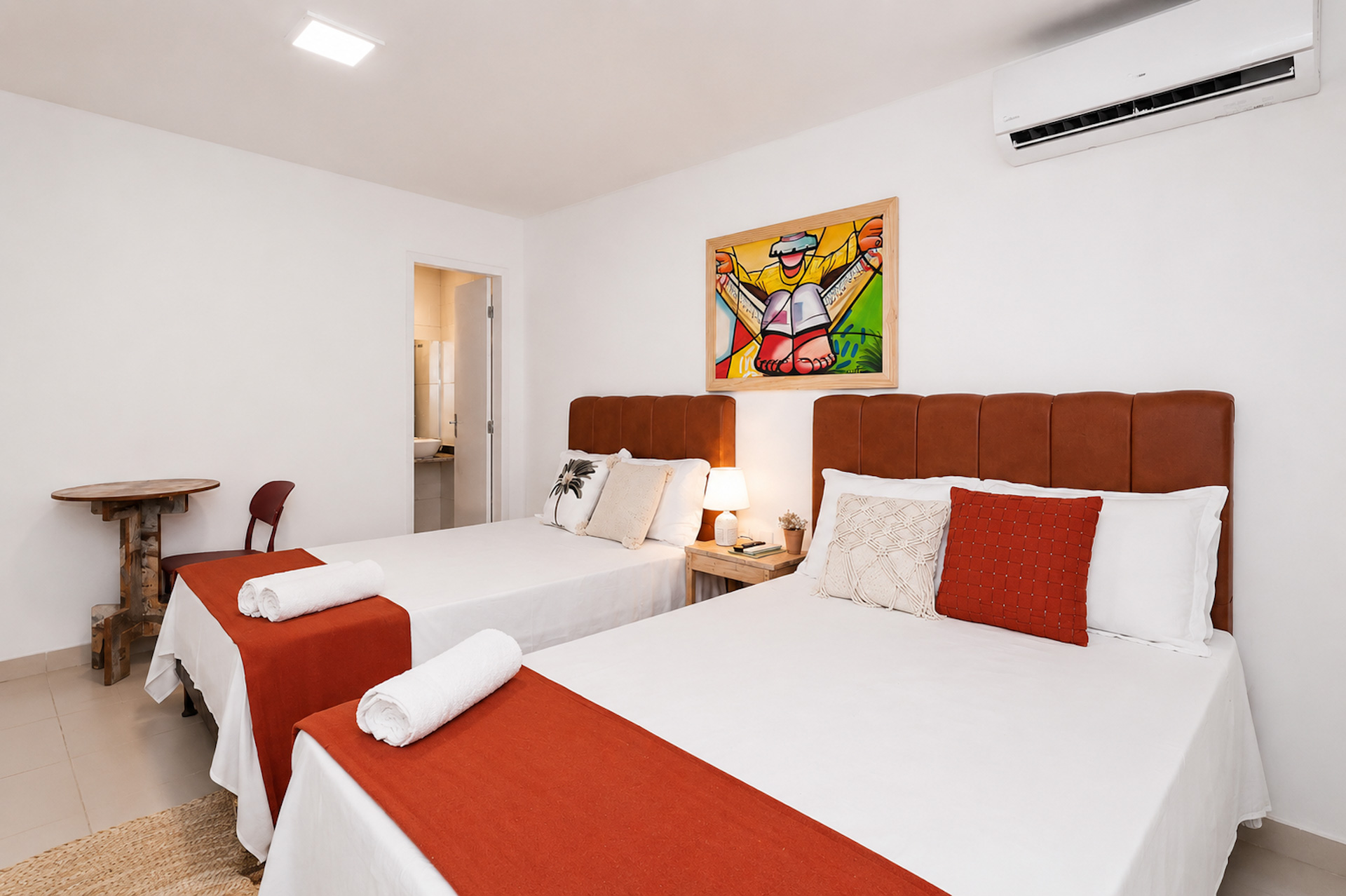 Quarto com duas camas de solteiro, mantas terracota e quadro colorido