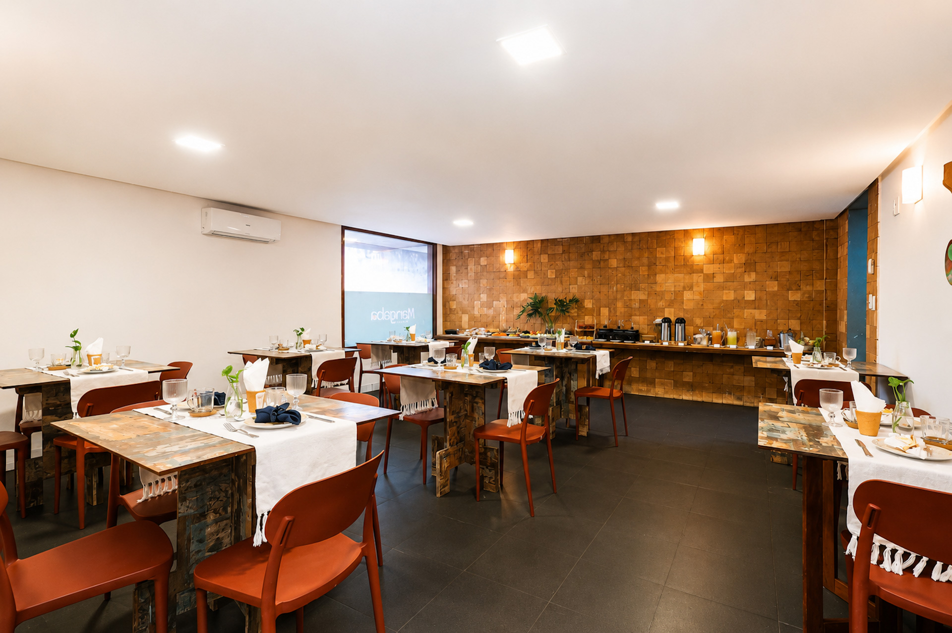 Salão de café da manhã com mesas e cadeiras vermelhas